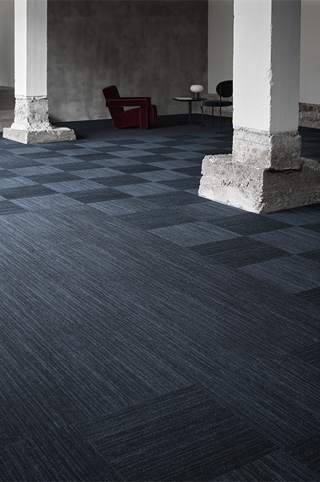 Vast room with big concrete pillars and blue toned carpet tiles for flooring