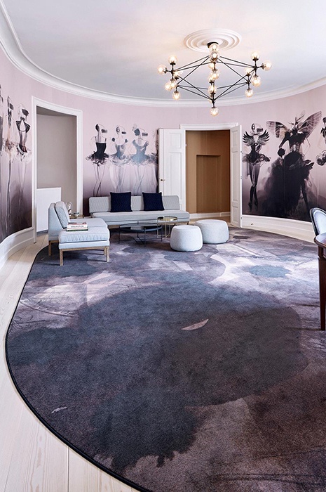 Office Club Kopenhagen Gemütlicher Raum mit rosa und grau Tapeten mit grossen Modezeichnungen und farblich passendem Teppich von ege