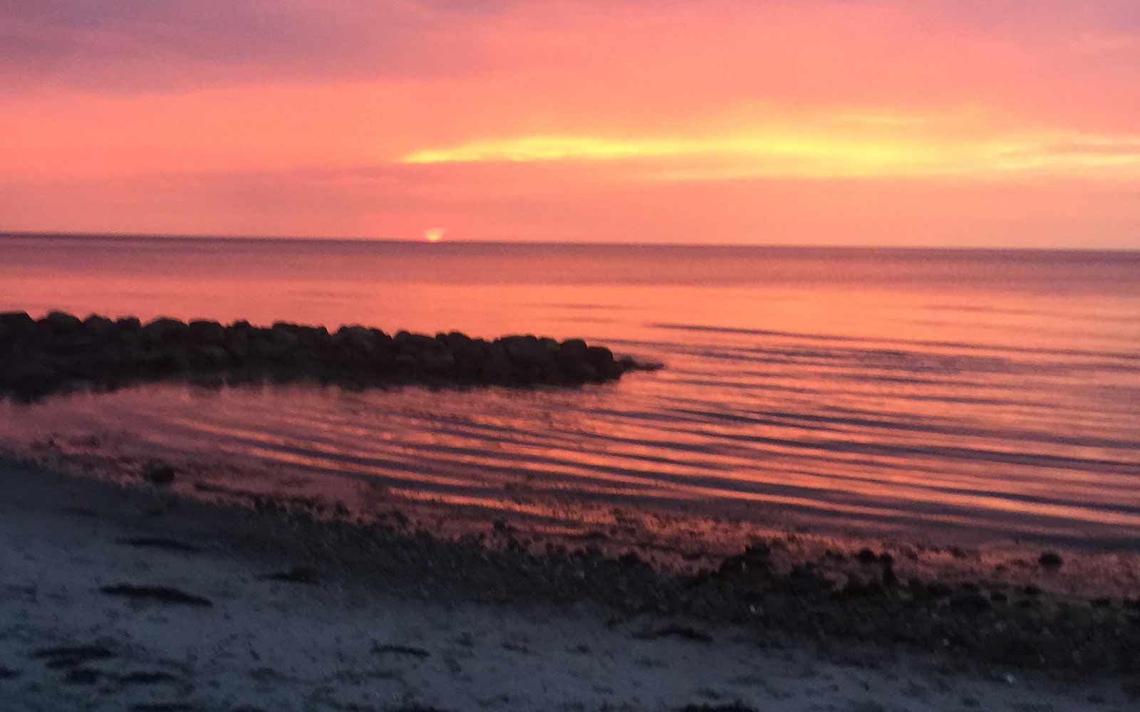 Coral, die Pantone-Farbe des Jahres 2019: Sonnenbestrahlte orange-rosa Wellen am Strand
