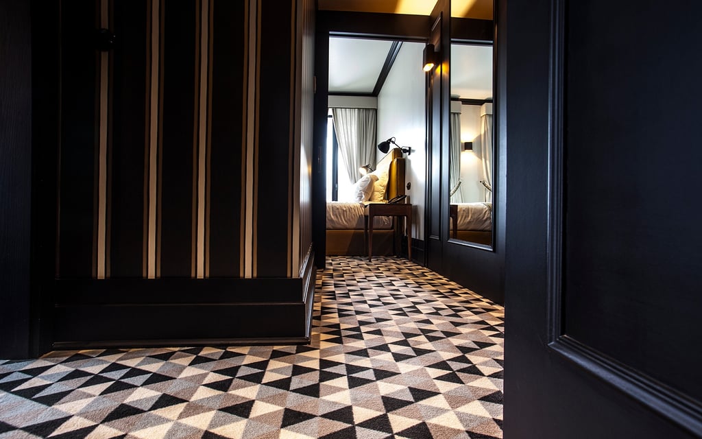 Hotelteppich: Dunkle Wandpaneelen und gemusterter Teppich srogt für eine gemütliche Atmosphäre im Hotelzimmer