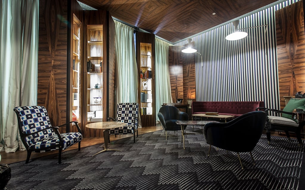 Hotelteppich: Die Kombination aus dunklem Teppich, holzverkleideten Wänden und gepolsterten Sitzmöbeln gibt der Hotellobby eine gemütliches Ambiente 