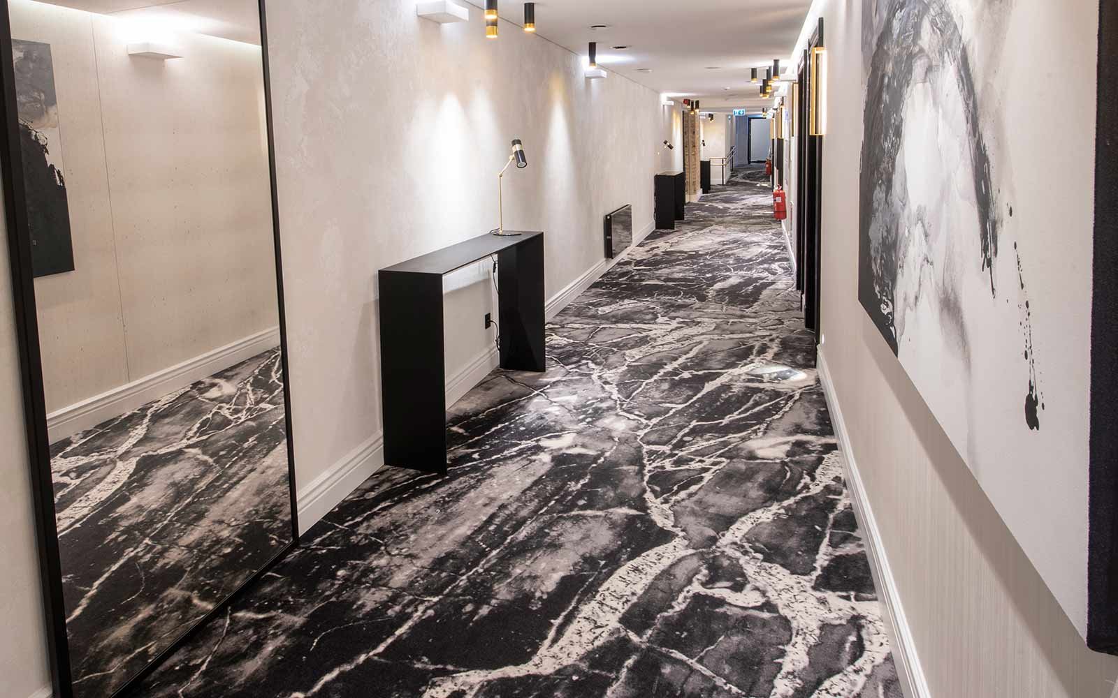 Hotel Teppichboden: Hotelflur mit Teppichboden in Marmoroptik und goldenen Akzenten in der Dekoration so wie heller Wandgestaltung